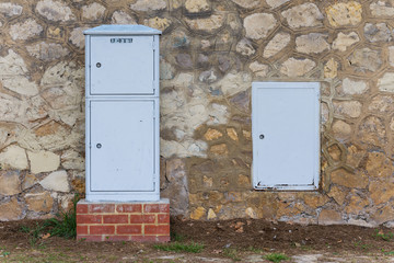 Cajas eléctricas junto a un muro de piedra