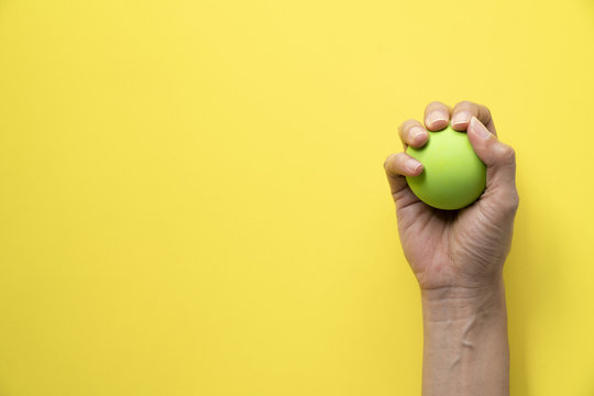 Woman Holding Stress Ball On Yellow Background