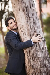 Businessman embrace a tree trunk