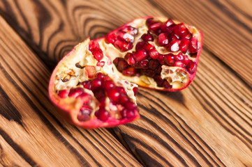 One broken half of red ripe fresh pomegranate on old brown weathered rustic planks