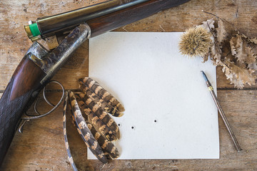 Concept d& 39 histoires de chasse : fusil de chasse, cible vers le bas, plumes de faisan et stylo vintage sur fond de bois ancien