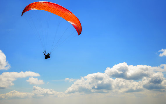 Paraglider floating in the air against the sky.