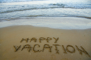 Happy vacation written on the sand. Relax and happiness concept.