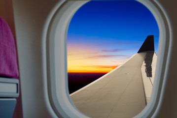Fototapeta na wymiar airplane wing on airplane window view at sunset