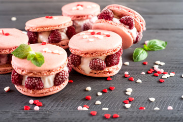 Tasty pink macaroons with raspberry on the wooden background