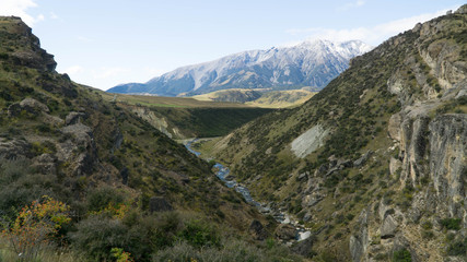 View of small autumn valley crossed by mountain stream, Arthurs Pass, New Zealand
