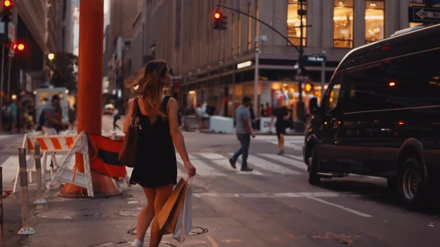 Young beautiful woman walking with shopping bags, crossing the traffic road in downtown of New York, America.