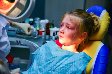 A little girl at the dentist at the reception sits on an armchair in the doctor's office.