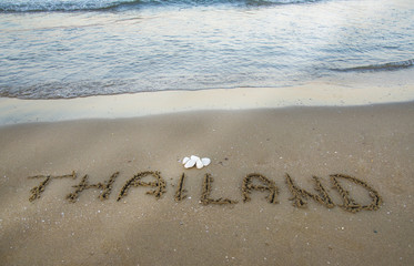 Thailand written on the sand on the beach.
