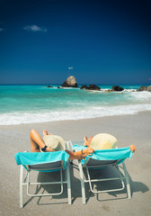 Couple on sunbeds relaxing at the beach in Lefkada