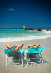 Couple on sunbeds relaxing at the beach in Lefkada Greece
