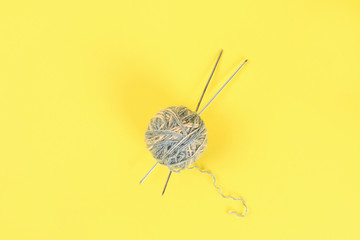 A ball of wool with knitting needles and knitted socks on a color pastel table. Needlework.