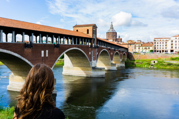 Naklejka premium Blonde girl watching the Ticino River near Ponte Coperto in Pavia, Lombardy, Italy