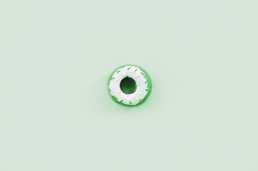 Single small plastic donut lies on a pastel colorful background. Flat lay minimal composition. Top...
