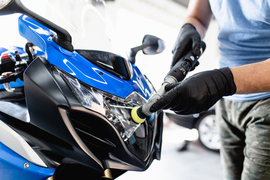 Fototapeta Motorcycle detailing - Man with orbital polisher in repair shop polishing motorcycle. Selective focus.