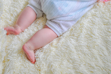 The legs of a small child on a soft blanket.