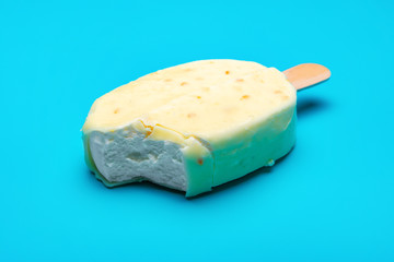 white popsicle with a bite on blue background