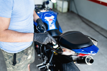 Motorcycle detailing - Man with orbital polisher in repair shop polishing motorcycle. Selective...