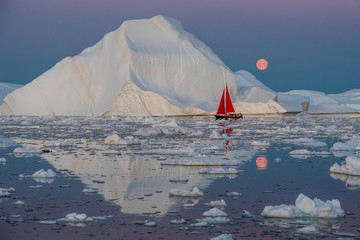Greenland midnight moonrise mirror panorama with red sail ship	
