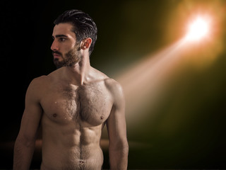 Fototapeta na wymiar Handsome young muscular man shirtless, on black background in studio shot