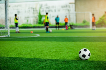 Obraz na płótnie Canvas Football on green artificial turf with blurry soccer players background.