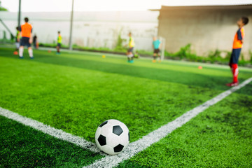 Football on green artificial turf with blurry soccer players background.