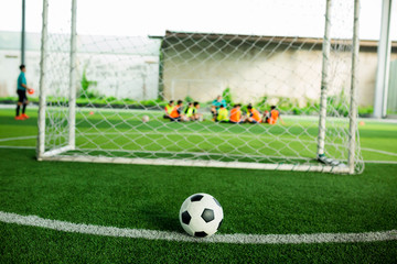 Football on green artificial turf with blurry soccer players background.