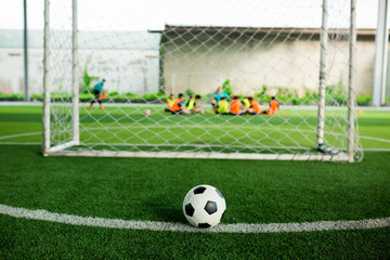 Football on green artificial turf with blurry soccer players background.