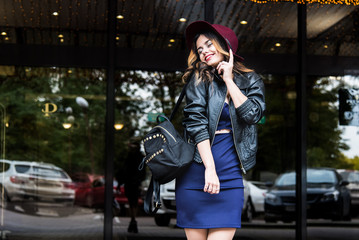 Young fashion woman in casual clothes and black leather jacket over urban city background autumn portrait. Hipster girl posing at street. Fashionable long hair model in elegant autumn clothes.