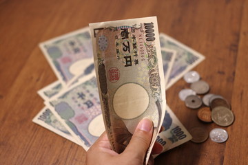 日本円(10000円札)を握る手とたくさんの紙