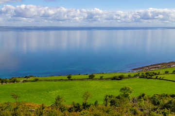 Farms in Burren way trail with Galway bay in background