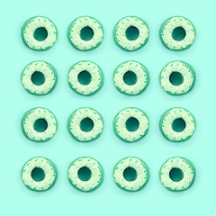 Many small plastic donuts lies on a pastel colorful background. Flat lay minimal pattern. Top view
