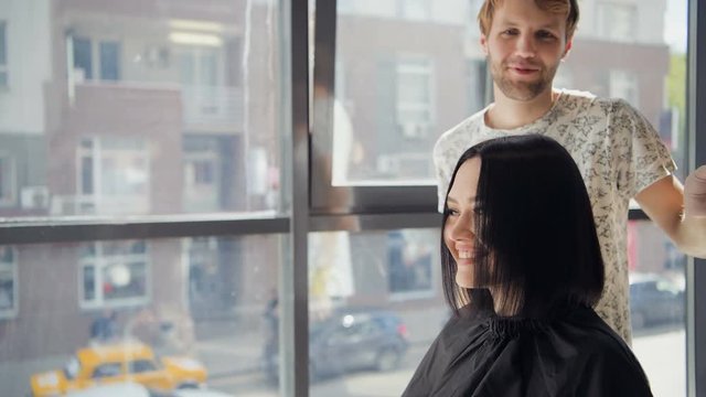 Professional hairdresser discussing female customer preferences in barbershop, choosing new hairdo