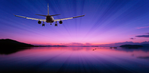 Fototapeta na wymiar Airplane flying over tropical sea at beautiful light sunset or dramatic sky sunrise scenery background