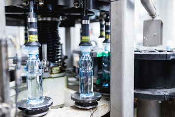 Bottling plant - Water bottling line for processing and bottling pure spring water into blue bottles. Selective focus.