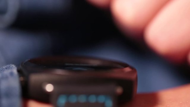 Close-up view of white kid's hand with black smartwatch. Child learning to use his new modern gadget with touch screen. Shallow depth of field. Real time full hd video footage.