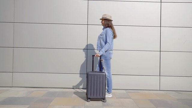 young woman traveler is going alone to a terminal, she is carrying her suitcase