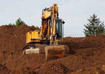 Front view of an excavator on a small hill of earth digged by itself