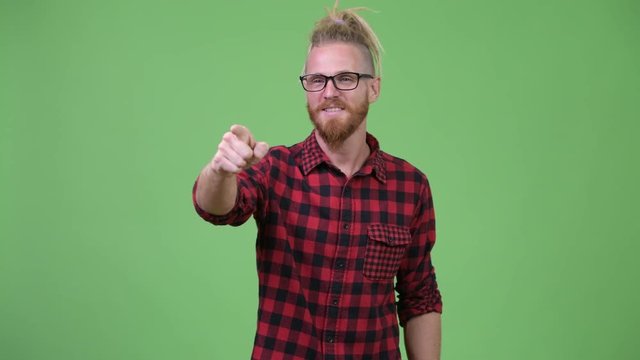 Happy handsome bearded hipster man with dreadlocks pointing finger
