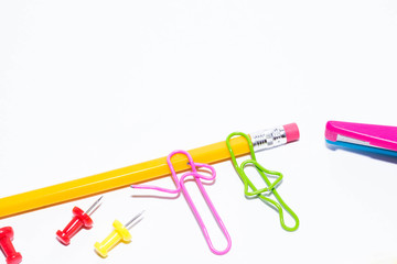 Two paper clips talking while lying on a white floor and on a pencil. Miniature school life and back to school concept with copy space white background. 