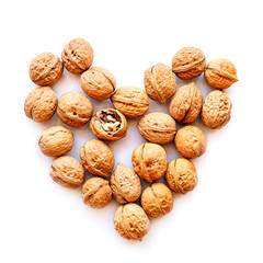 whole walnuts scatter with one cracked nut in heart shape isolated on white