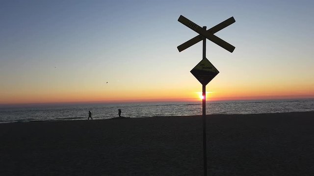 Strand auf Sylt bei Sonnenuntergang Schild mit Warnung vor Str&ouml;mung im Vordergrund