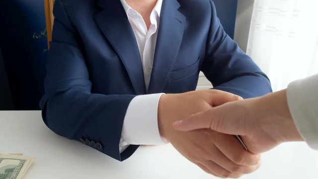 Closeup 4k footage of person giving money as bribe while shaking hand to corrupted politician