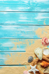 sea rope with many different sea shells on the sea sand on a blue wooden background. Top view