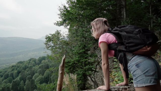 The girl looks at the forest off the cliff