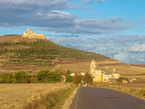 A prominent castle in ruins up on the hill and the Church of Santa María del Manzano along the road - Castrojeriz, Castile and Leon, Spain