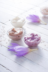 beauty product samples and autumn crocus herbal flower on white wooden table