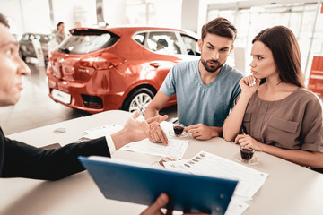 Young Family Are Choosing A New Car In Showroom.