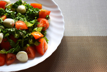 Festive dish for the New year and Christmas on a beautiful white dish. Salad of cherry tomatoes, green lettuce and mozzarella cheese. Delicious healthy food with fresh vegetables. Vegetarian food.