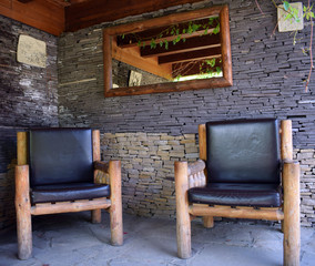 On the veranda leather chairs with wooden legs. Lounge. The interior is decorated in a rustic style. Exclusive vintage wooden furniture.